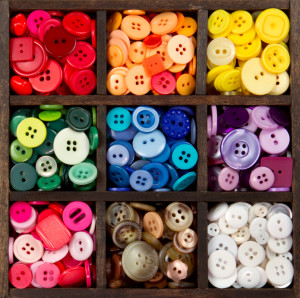 an assortment of buttons in a rainbow of colors, in a printers box